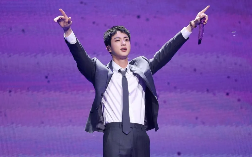 Mulher que beijou Jin, membro do BTS, na bochecha durante seu ‘evento de abraço’ no ano passado, acusada de assédio sexual